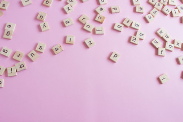 Random wooden letters on pink background