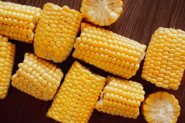 Close-up of ears of corn cut into pieces fresh corn on a wooden background. Top view.