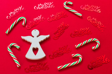  The figure of a white angel Christmas candy and red shiny lettering with Christmas on a red background.