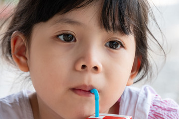 Cute Little Asian Girl eats chocolate milk.