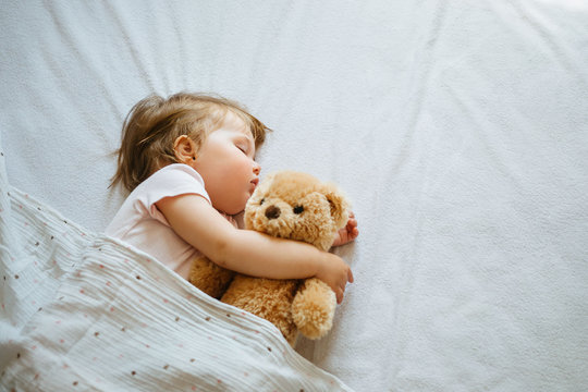 Little baby sleeping on bed at home with soft toy. Free space