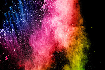 Abstract multicolored powder explosion on black background. Color dust particle splattered on background.