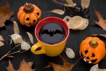 Cup of tea with reflection of bat on dark wooden background. Halloween celebration concept. Copy space