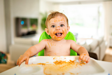 A Little baby eating her dinner and making a mess