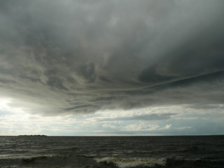 huge low dark clouds approaching the shore from the sea
