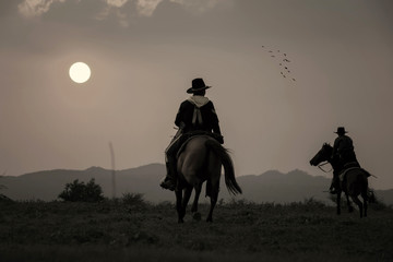 The silhouette of two cowboys, who were traveling with his horse