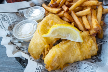 Fish & Chips Served with Fries and a Wedge of Lemon on Newspaper