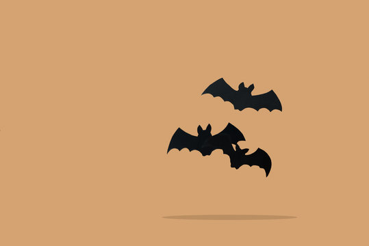 Paper craft. Black bats flying against orange background. Halloween celebration concept. Copy space