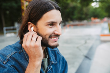 Smiling brunette hipster man listening to music