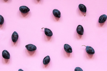 Ripe plums on pink background. Fresh fruits top view, flat lay.