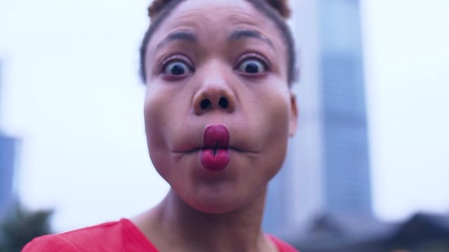 Close up of one happy young African woman in red dress making funny face in the urban street of Chengdu China joyful young people make faces Weird facial expression in the city 