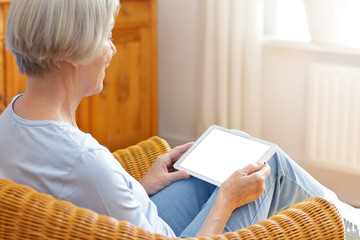 Video call mock-up template: elderly woman at home talking with tablet computer on her lap, blank...