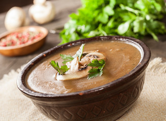 Delicious creamy mushroom soup with parsley and close-up on a dark background.