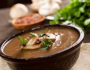 Delicious creamy mushroom soup with parsley and close-up on a dark background.