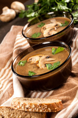 Delicious creamy mushroom soup with parsley and close-up on a dark background.