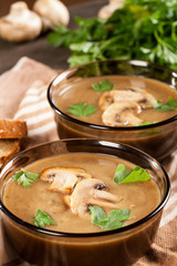 Delicious creamy mushroom soup with parsley and close-up on a dark background.