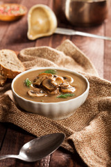 Delicious creamy mushroom soup with dill and close-up on a dark wooden background.