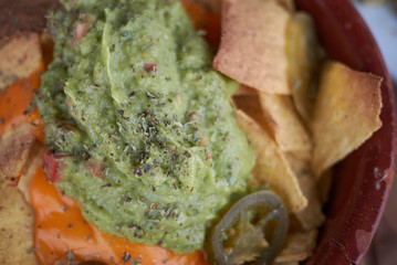 Nachos chips with guacamole, melted cheddar and chilli peppers