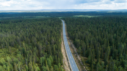  Aerial view from above of highway through the green summer forest in summer Lapland. Drone photography.