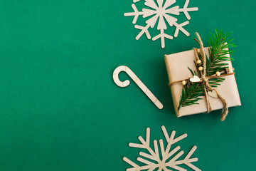 Christmas and New Year holidays composition. Gift box, christmas tree and snowflakes on a green background. Top view, copy space