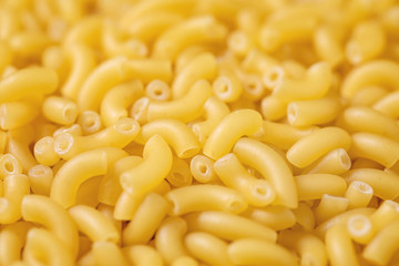 Heap of raw uncooked italian pasta coquillettes over brown texture background. Food background. Macro, close up