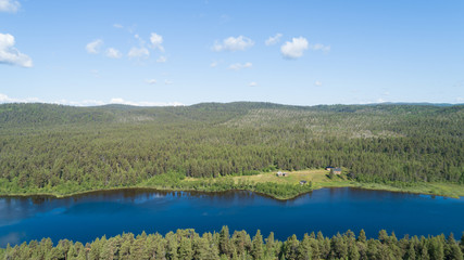 Forest river panorama. Green forest, old huts and hills on background. Lapland, Lemmenjoki.