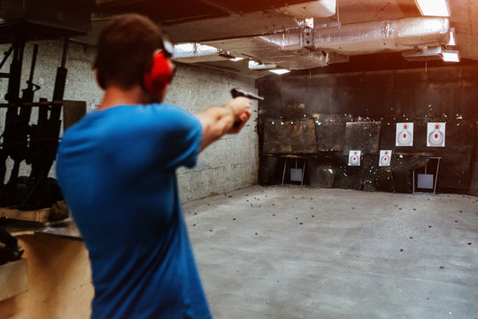 firing pistol at target in indoor shooting range