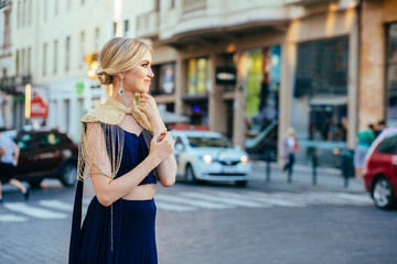 Obraz premium Portrait european woman excite happy emotions walking outdoor in city street with golden evening light background. Jewelry set traditional India costume sari.Girl sensual look bindi tikka.