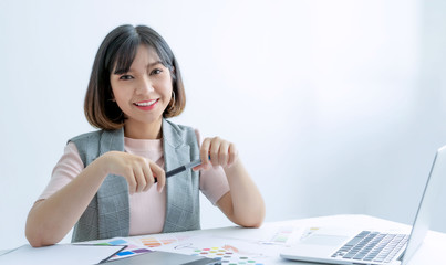 Portrait of young asian designer sitting at graphic studio in front of laptop and computer while working online.Happy asian women successful programmer and designer sitting in office room.