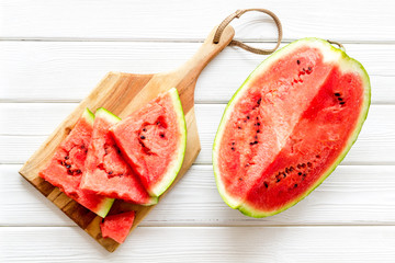 Cut watermelon for break with fruit on white wooden background top view