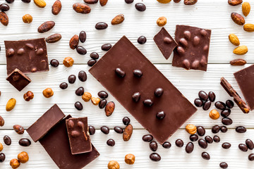 Cook homemade chocolate with bars, nuts, coffee beans on white wooden background top view