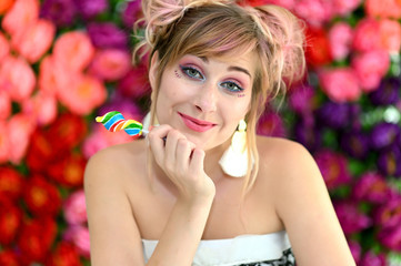A close-up portrait of a cute happy cool blonde girl with colored hair on a multi-colored background with candy in her hands. Smiling in various poses, beauty, holiday.