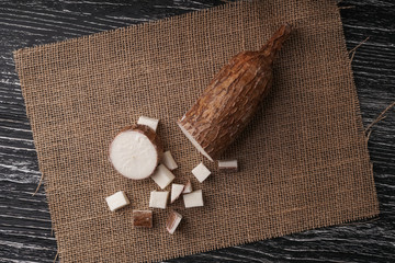 Sliced yucca root on a sackcloth on a black wooden table - obrazy, fototapety, plakaty