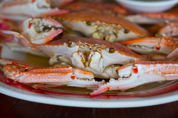 Steamed blue crab in plate on wood table.