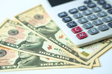 Fototapeta premium Calculator on ten dollars banknotes on a white background. Concept of Calculation of income and expenses