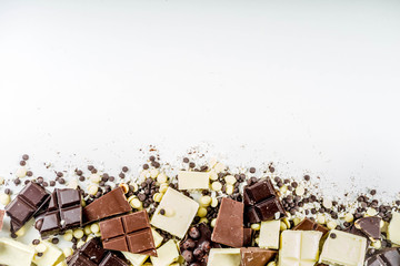 Assorted different types of chocolate. Broken pieces of dark, milk and white chocolate, with nuts, cooking chocolate, shavings. top view copy space