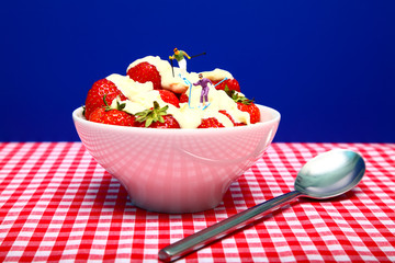 Conceptual image of miniature figures skiing in a bowl of strawberries and cream