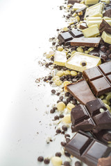 Assorted different types of chocolate. Broken pieces of dark, milk and white chocolate, with nuts, cooking chocolate, shavings. top view copy space