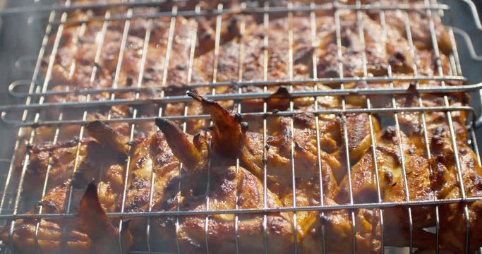 A close up of the cooking chickens on grill