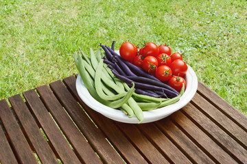 Freshly harvested beans and cherry tomatoes on a wooden table