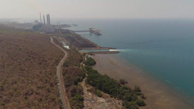 power station with spillway by sea with smoking pipes, paiton java, indonesia. aerial view power plant in asia.
