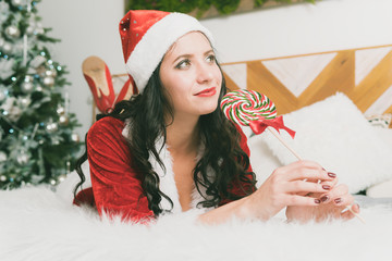 Funny Christmas Girl Holding a Candy Lollipops. Beautiful expressive woman in sweet Christmas fantasy portrait with lollipops