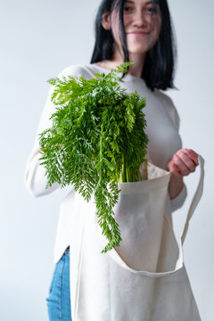 young woman holding textile glocery bag with vegetables