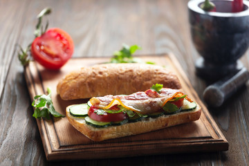 Delicious Sandwich with Bacon and Vegetables on a wooden board