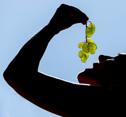 Close-up of a woman about to eat a bunch of white grapes
