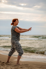 A woman makes tai chi exercises for relaxation on the beach. Concept: health and vacation