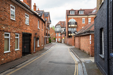Narrow street lined with traditional brick residential buildings on a cloudy spring day. Eaton, England, UK.