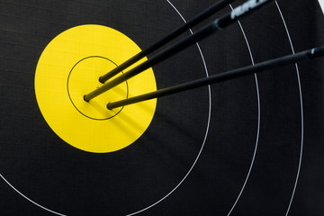 Three arrows in the center of black and yellow archery target. Accuracy and precision concept.