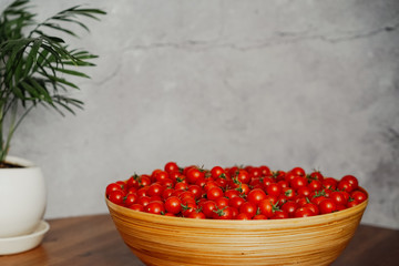  Large wooden bowl with cherry tomatoes. seasonal vegetables