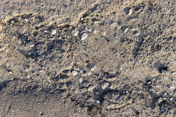 the crumbling piece of asphalt with gravel stones